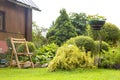 Beautiful garden with blooming flower beds and a wooden garden chair near country house Royalty Free Stock Photo