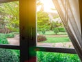 Beautiful garden Nature behind window lighting flare bright in the morning. White frame and dark handle. Look through the glass.