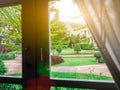 Beautiful garden Nature behind window lighting flare bright in the morning. White frame and dark handle. Look through the glass.