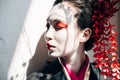 Beautiful geisha with red and white makeup in sunlight with shadows