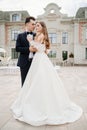 beautiful, gentle and happy bride and groom hugging on background of building Royalty Free Stock Photo