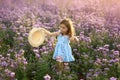 Beautiful gentle sweet cute girl in a blue dress holds a hat in hands and looks towards copy space.