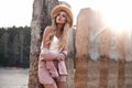 Beautiful gentle young lady is posing in straw hat in the sunlight. Countryside landscape, forest nature at the background. Summer