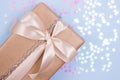 Beautiful gift box with beige bow and pink glitter stars on a pastel blue background. Flat lay