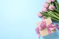 Beautiful gift box and bouquet of pink tulip flowers on light blue background, flat lay. Space for text Royalty Free Stock Photo