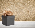 Beautiful gift box on white wooden table against shiny golden background, bokeh effect. Space for text Royalty Free Stock Photo