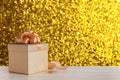 Beautiful gift box on white wooden table against shiny golden background, bokeh effect. Space for text Royalty Free Stock Photo