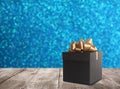Beautiful gift box on wooden table against shiny light blue background, bokeh effect. Space for text Royalty Free Stock Photo