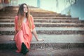 Beautiful gil sitting on outdoors stairs wearing red dress