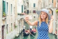 Beautiful gir traveler tourist in blue polka dot dress make selfie in venice Italy. Attractive blonde fashion model young woman