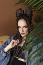 Beautiful girl with an afro cornrows hairstyle, wearing a casual denim jacket, is resting on a chair standing on an old carpet