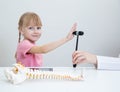 A beautiful girl aged 5 years applies the palm of her hand to the neurological hammer of a neuropathologist doctor. Treatment and