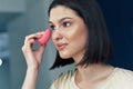 Beautiful girl applying makeup on her face during online lessons. Pretty young brunette woman making herself makeup Royalty Free Stock Photo