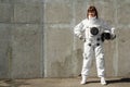 Beautiful girl astronaut without a helmet on the background of a gray wall. Fantastic space suit