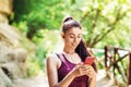 Beautiful girl athlete chooses a track in a smartphone. Portrait of a beautiful sports model in the park with a phone in his hand