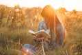 Beautiful girl in autumn field reading a book. The girl sitting on a grass, reading a book. Rest and reading. Outdoor reading Royalty Free Stock Photo