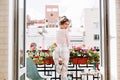 Beautiful girl from back in pajamas on balcony in sunny morning. She  raises leg and looks excited to camera. Royalty Free Stock Photo