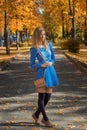 Beautiful girl with a bag in a short dress and leggings walking along the path in autumn Park Royalty Free Stock Photo