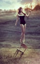 Beautiful girl balances on back of chair outdoors. Royalty Free Stock Photo