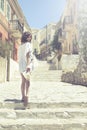 Beautiful girl bathed in sunshine walking in ancient city Symi