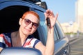 The beautiful girl became the happy owner of the new car. Holds keys in his hands smiling to squinting from the sun Royalty Free Stock Photo