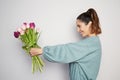 Beautiful girl with big bouquet flowers tulips in hands on a light background