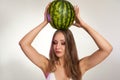 Beautiful girl with big whole watermelon on her had, isolated on studio background. Cosmetics, food, beauty concept, text space