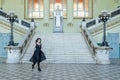 Beautiful girl in black dress running down wide stairs in hall checkered floor