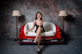 A beautiful girl in a black dress is sitting on an unusual handmade sofa. Sofa from the car seat. Royalty Free Stock Photo