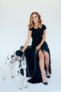 Beautiful girl in a black dress on a white background with a dalmatian dog Royalty Free Stock Photo