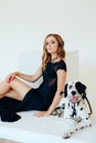 Beautiful girl in a black dress on a white background with a dalmatian dog Royalty Free Stock Photo