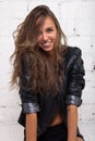 Beautiful girl in black leather jacket looking up and smiling at the camera. White brick wall, not isolated Royalty Free Stock Photo