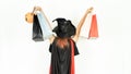 Beautiful girl with black and orange hair in black dress and turn around witch hat is holding shopping bags. Halloween concept Royalty Free Stock Photo