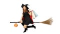 Beautiful girl with black and orange hair in black dress and witch hat is riding staff with shopping bags on white background for Royalty Free Stock Photo