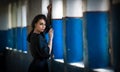 Beautiful girl in black posing in an old hall with columns blue painted. Attractive long hair brunette, side view against wall