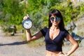 Beautiful girl in a black top and sunglasses holding a clock. Royalty Free Stock Photo
