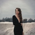 Beautiful girl in in black vintage dress with curly hair posing on the sand. Woman in retro dres. Worried sensual emotion . Retro Royalty Free Stock Photo