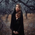 Beautiful girl in in black vintage dress with curly hair posing in the woods. Woman in retro dress lost in the forest. Worried sen Royalty Free Stock Photo