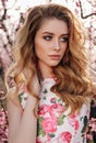 beautiful girl with blond hair in elegant clothes posing in blooming peach garden Royalty Free Stock Photo