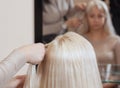 Beautiful girl with blonde hair, hairdresser weaves a braid close-up, in a beauty salon. Royalty Free Stock Photo