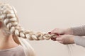 Beautiful girl with blonde hair, hairdresser weaves a braid close-up Royalty Free Stock Photo