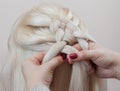 Beautiful girl with blonde hair, hairdresser weaves a braid close-up, in a beauty salon Royalty Free Stock Photo