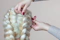 Beautiful girl with blonde hair, hairdresser weaves a braid close-up, in a beauty salon. Royalty Free Stock Photo