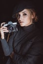 Beautiful girl blonde photographer in a strict suit and a cappie is holding an old retro camera in her hands Royalty Free Stock Photo