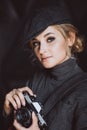 Beautiful girl blonde photographer in a strict suit and a cappie is holding an old retro camera in her hands Royalty Free Stock Photo