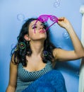 Beautiful girl is blowing soap bubbles with pink sunglasses.