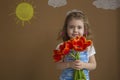 Beautiful girl in the blue dress with flowers tulips in hands on a light background with painted sun and clouds Royalty Free Stock Photo