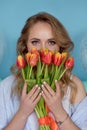 Beautiful girl in the blue dress with flowers tulips in hands on a light background Royalty Free Stock Photo