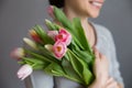 Beautiful girl in the blue dress with flowers tulips in hands on a light background Royalty Free Stock Photo