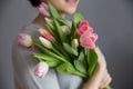 Beautiful girl in the blue dress with flowers tulips in hands on a light background Royalty Free Stock Photo